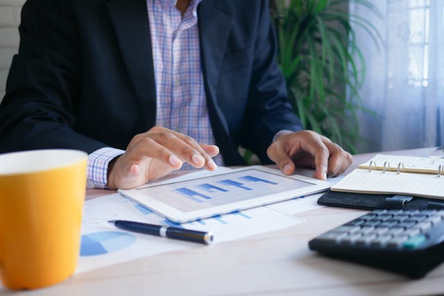 person looking over financial reports with a calculator on their desk