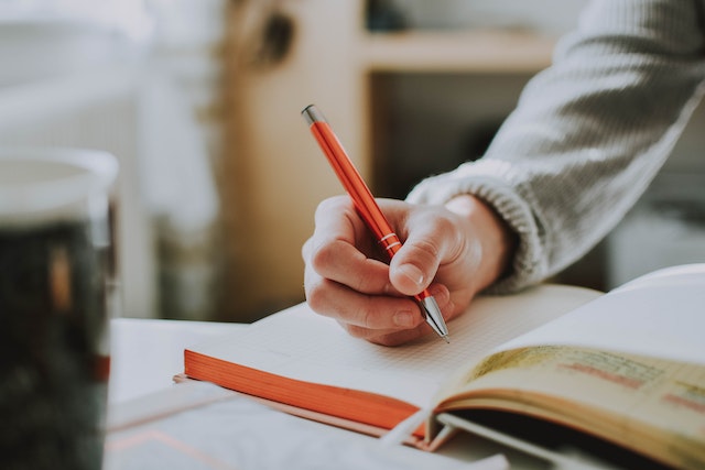 person-holding-a-pen-in-a-notebook