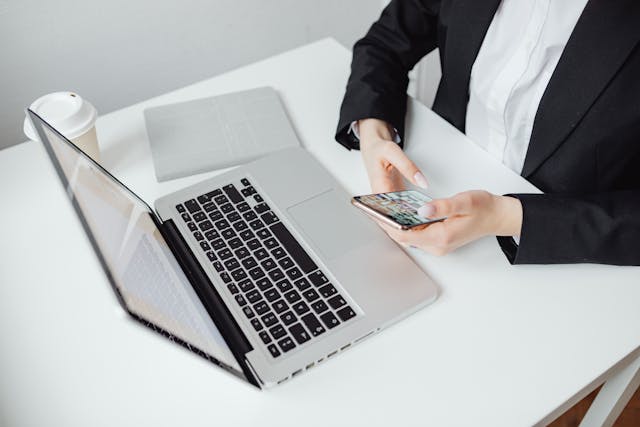 someone on their phone in front of an open laptop