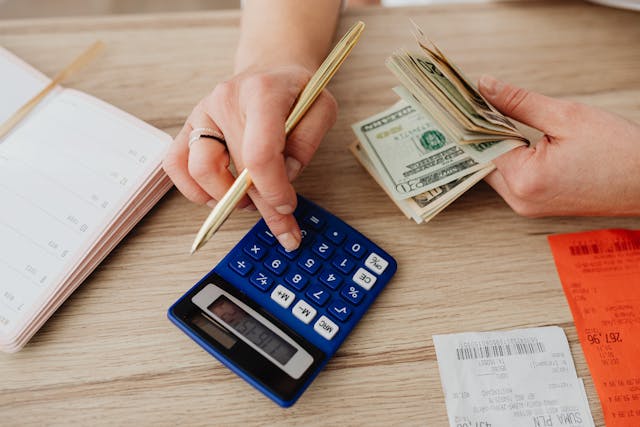 person calculating money and receipts using a calculator