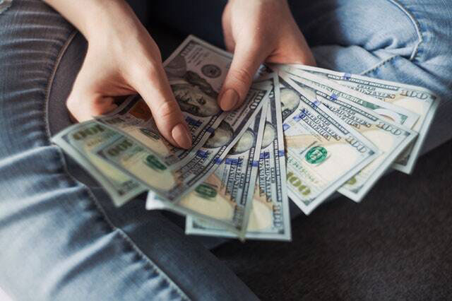 person holding several hundred dollars in us currency