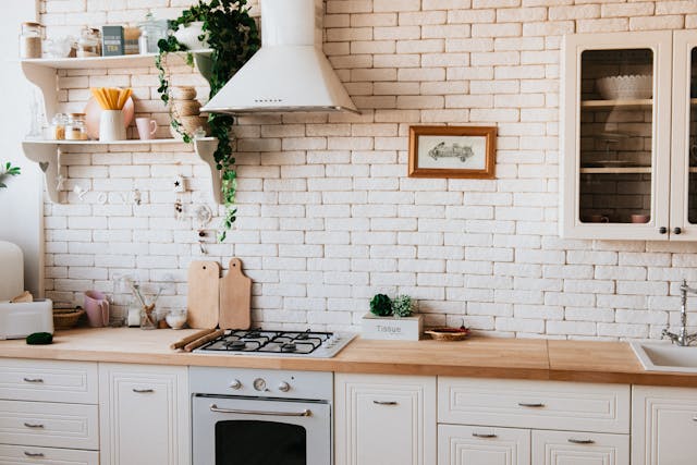 white brick kitchen with white cupboards and a wooden countertops